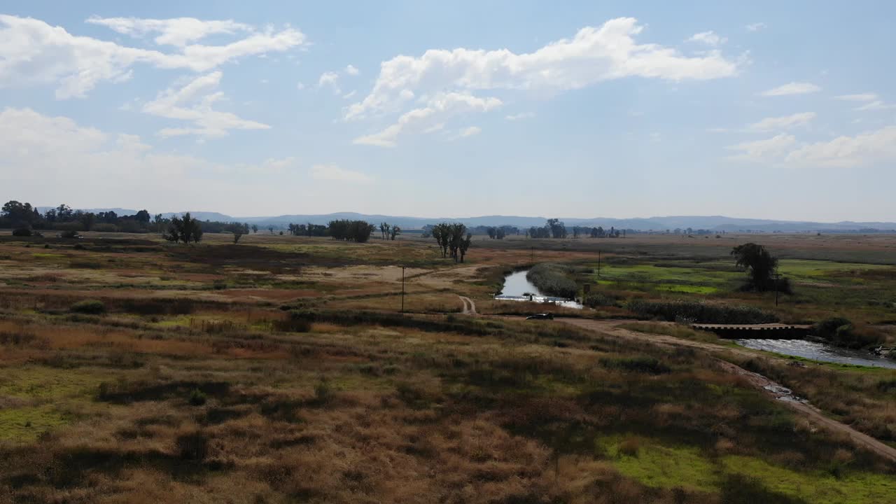 toma aérea de un dron del río que fluye bajo un puente remoto de grava en johannesburgo, sudáfrica