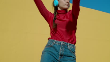 Close-up-of-Happy-Young-Woman-legs-dancing-wearing-red-converse-sneakers-on-a-concrete-floor-with-a-yellow-background