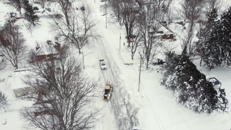 aerial overhead shot of snowplow turning around on snow covered residential street in fort erie, ontario after snow blizzard