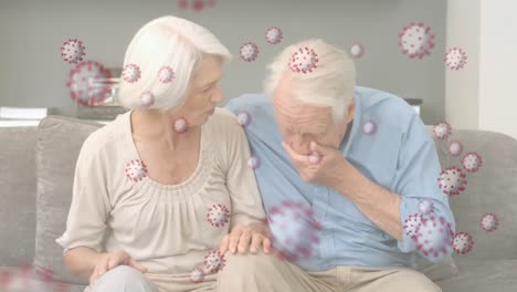 Animation-of-spreading-coronavirus-covid19-over-senior-Caucasian-couple-at-home-and-sneezing