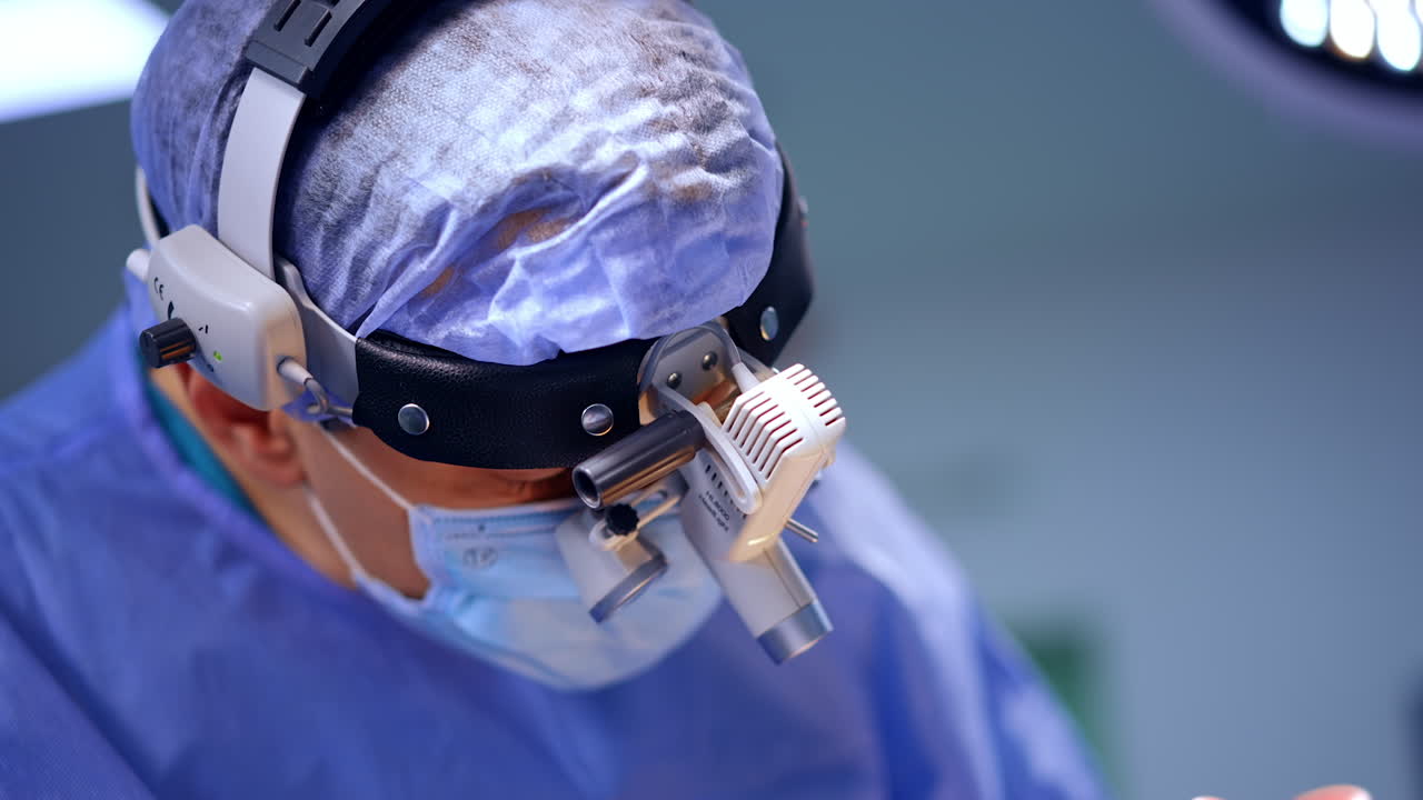 Close up of surgeon wearing magnifying headlight in neurosurgery. Neurosurgeon works with magnification device during complex brain operation. Medical precision is the main focus of this procedure