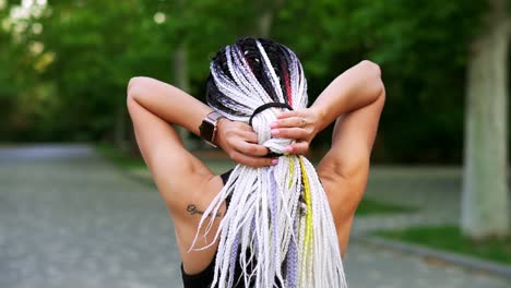 black and white dreadlocks on the back of a girl. rear view of a sporty girl combing hair with hair rubber for comfortable walk