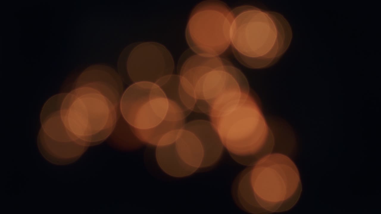 Lana d'acciaio che brucia, scintille di bokeh arancione tondo in movimento nell'oscurità.