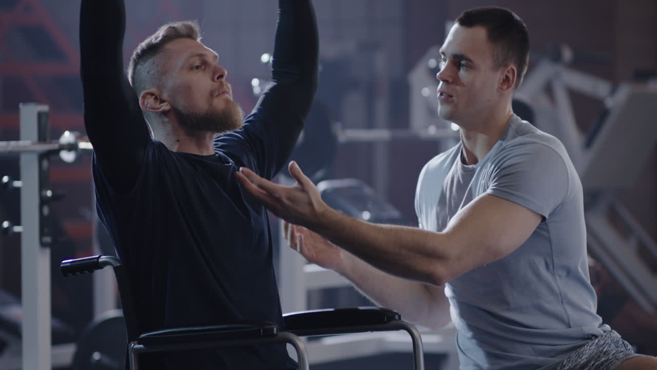 Man in Wheelchair Lifting Weights at Gym Confident Man in Wheelchair Performs Shoulder Press Exercise with Dumbbells at Modern Gym Demonstrating Strength Fitness and Determination