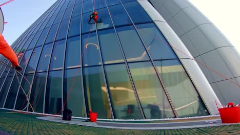 maintenance worker on rope at business district skyscraper cleaning windows, point of view