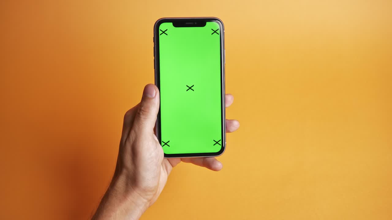 teléfono móvil con pantalla verde sobre fondo naranja, vista superior