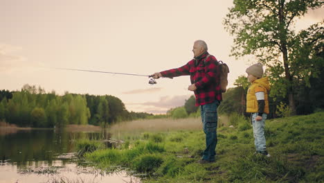 El-Abuelo-Está-Enseñando-A-Su-Nieto-A-Pescar.-El-Viejo-Pescador-Y-El-Chico-Divertido-Descansan-En-La-Orilla-Del-Lago.