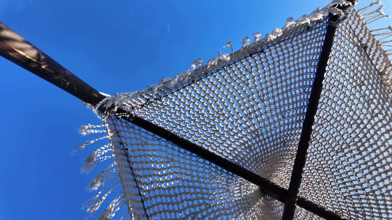 Shade umbrella beach Ksamil Albania luxury resort at Ionian Sea moving with wind, clear blue sky