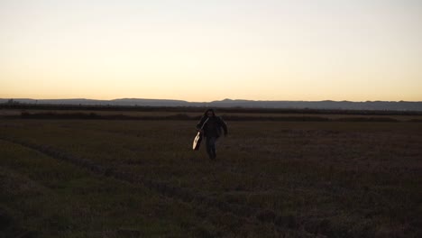 Man Running Through Fields at Sunset with Guitar