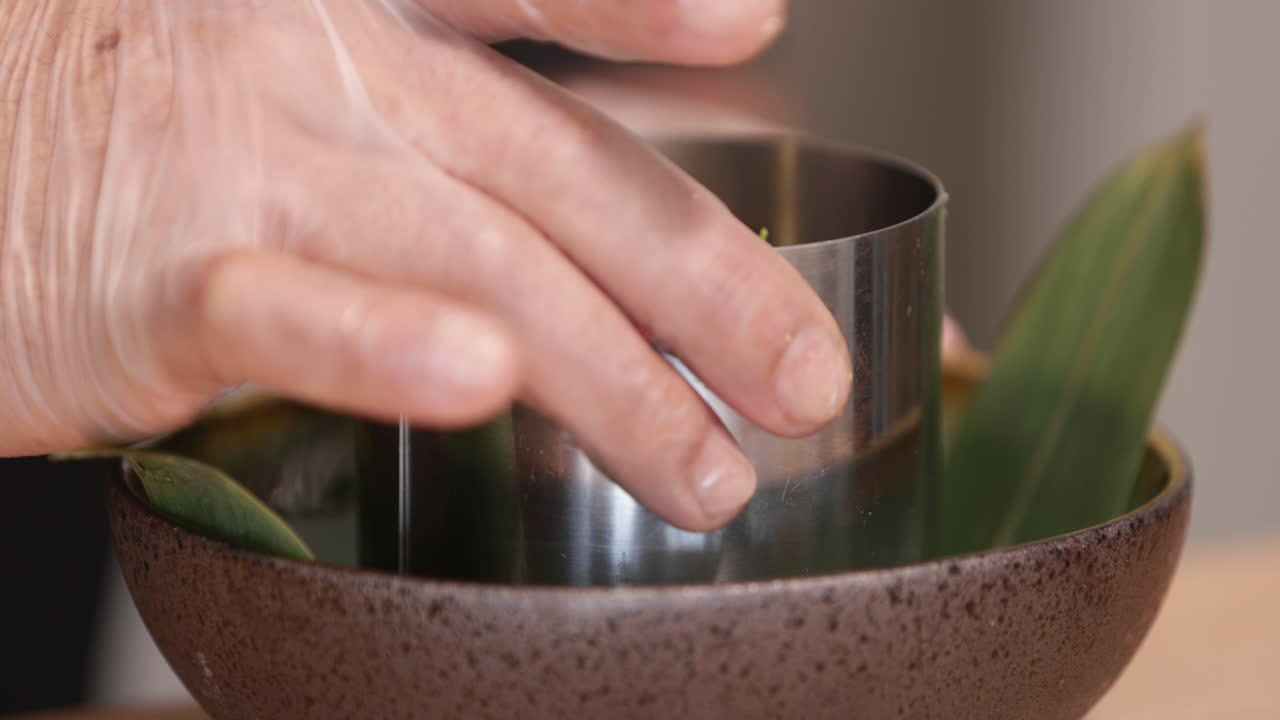 el chef con guantes levanta la moldeadora de acero inoxidable y deja al descubierto el tartar de atún con huevo de codorniz y caviar negro.