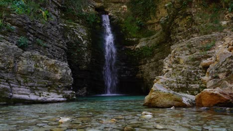 paisaje de cuento de hadas de cascada con agua cristalina rodeada de acantilados excavados en progonat, albania