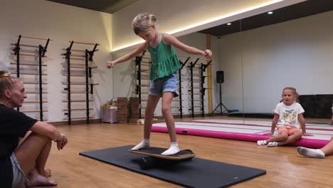 child practicing balance board in a gym