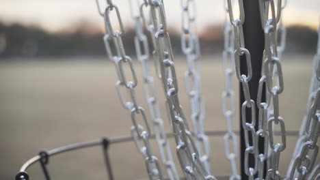 white disc golf disc is putted into the chains of a disc golf basket and is retrieved by disc golfer