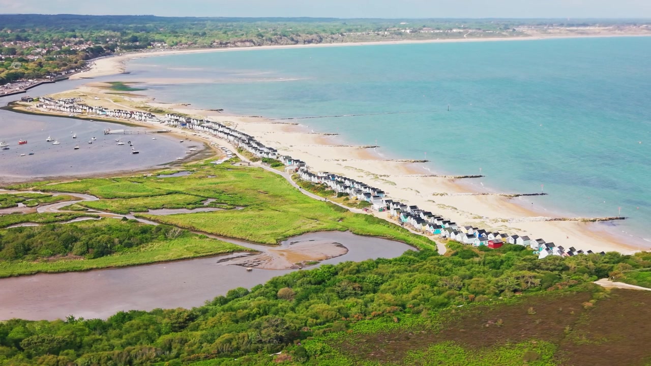 Droneoptagelser over Mudeford Sandbank med strandhytter, sandstrand, turkisblåt hav, Christchurch Havns vådområder, både og kystlandskab