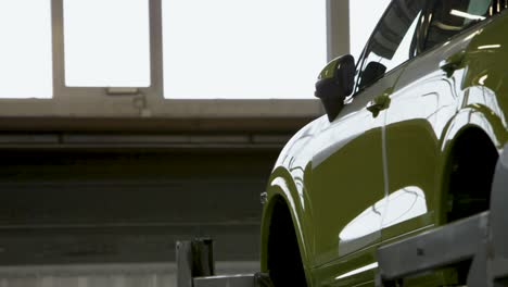 side view of a lime green car in a bright garage, light streaming through windows, partial view