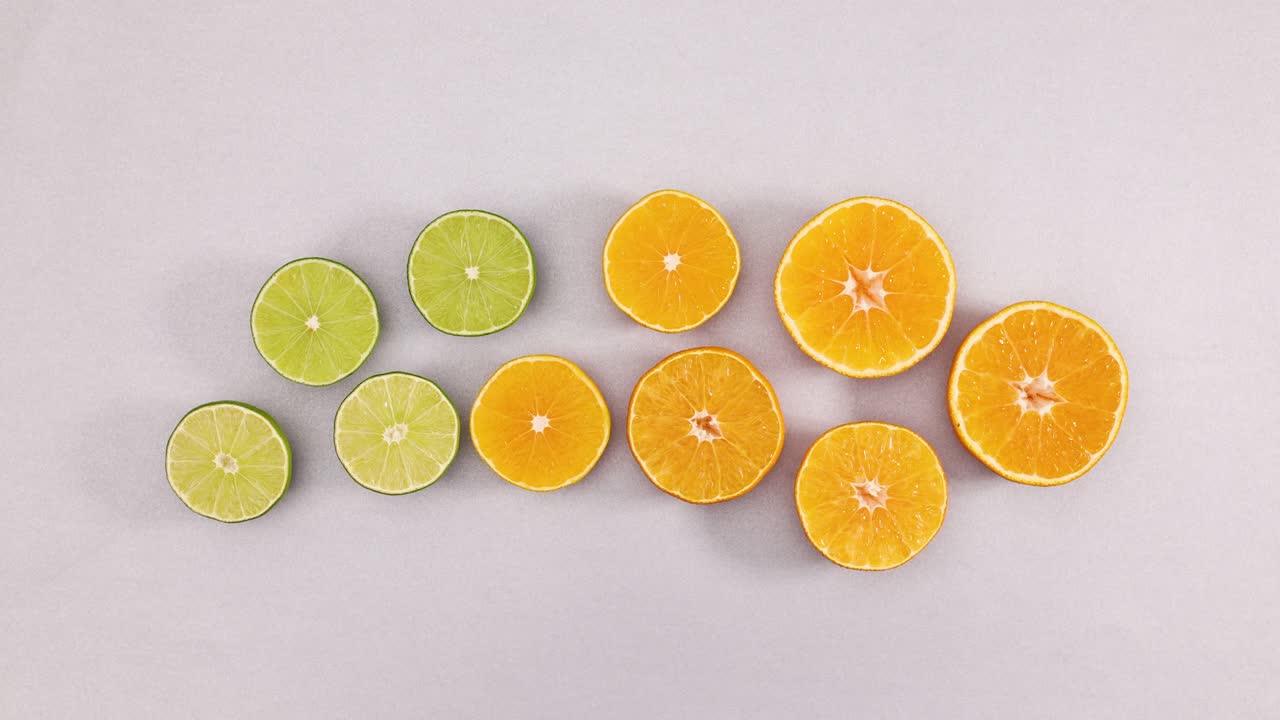 Slices of fresh limes and oranges rotating on silver theme. Stop motion