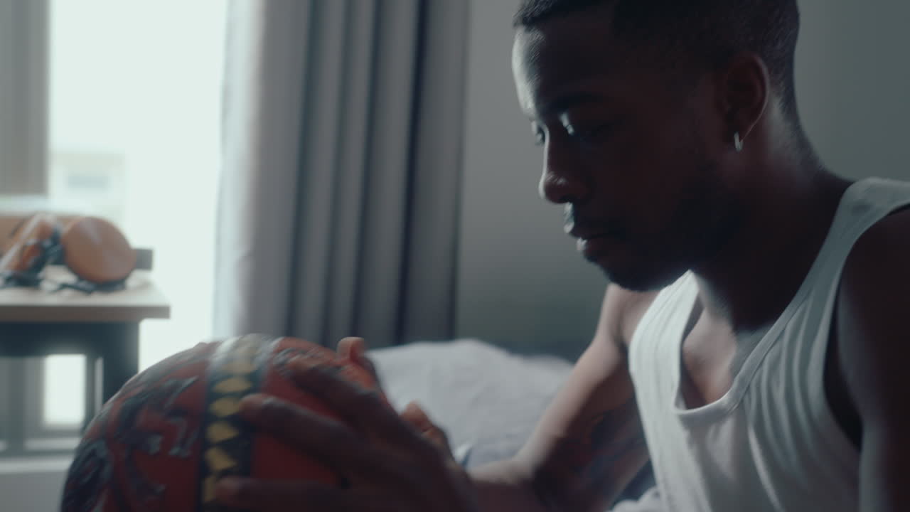 Young African American Man Playing with a Basketball in Bedroom