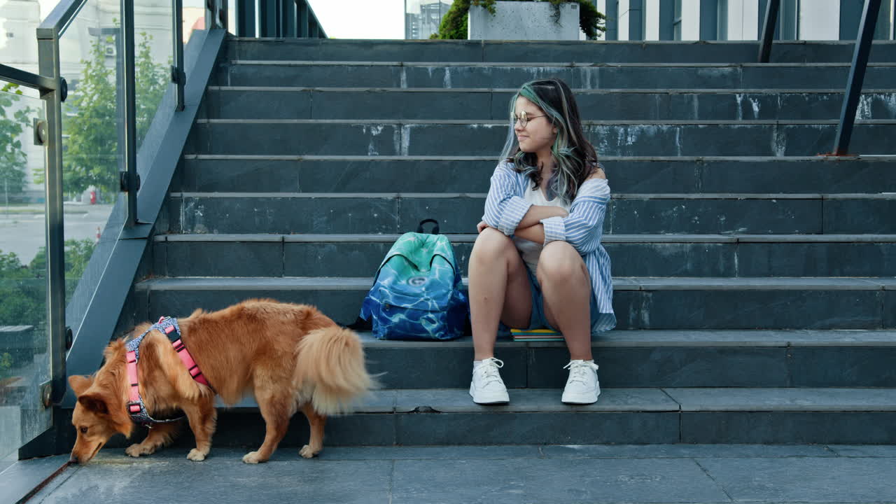 Teenager and dog sitting on outdoor stairs