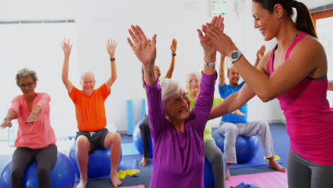 Vista-Lateral-De-Una-Entrenadora-Caucásica-Entrenando-A-Una-Mujer-Mayor-En-Ejercicio-En-El-Gimnasio-4k