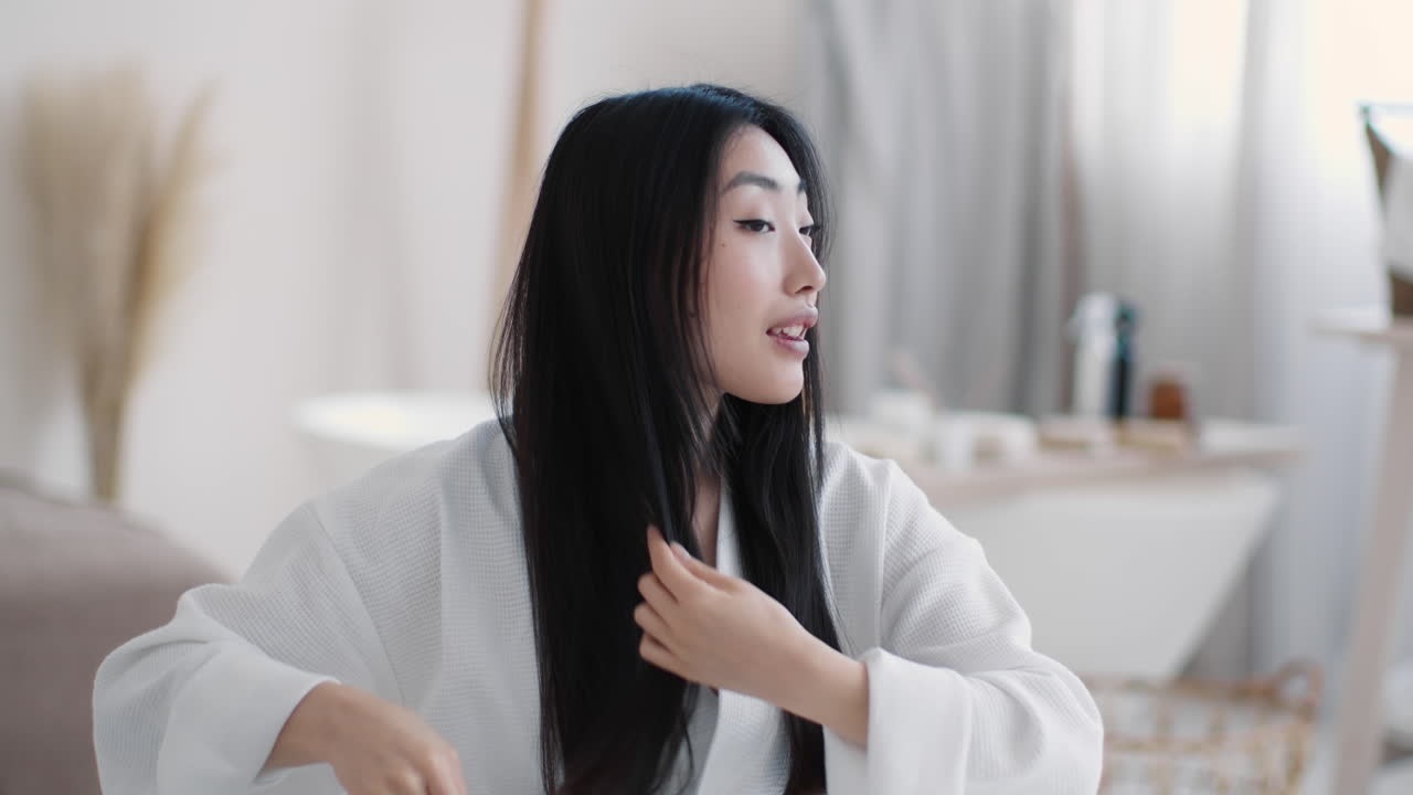 Woman combing her long hair in a bedroom