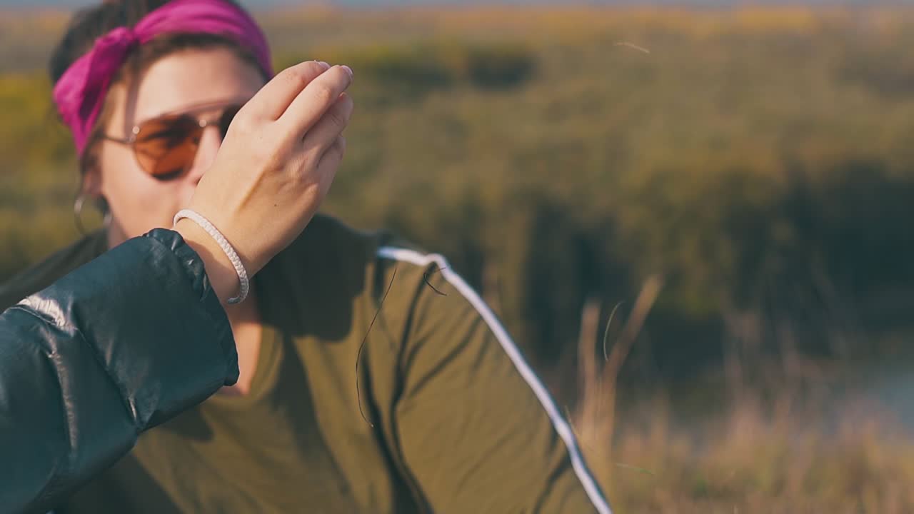 미소 짓는 젊은 여자가 잔디를  ⁇ 는 여자 손을 쳐다본다.