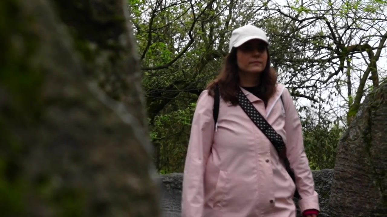 Escursionista donna che cammina su un sentiero circondata da una foresta lussureggiante e formazioni rocciose uniche a Zhangjiajie.