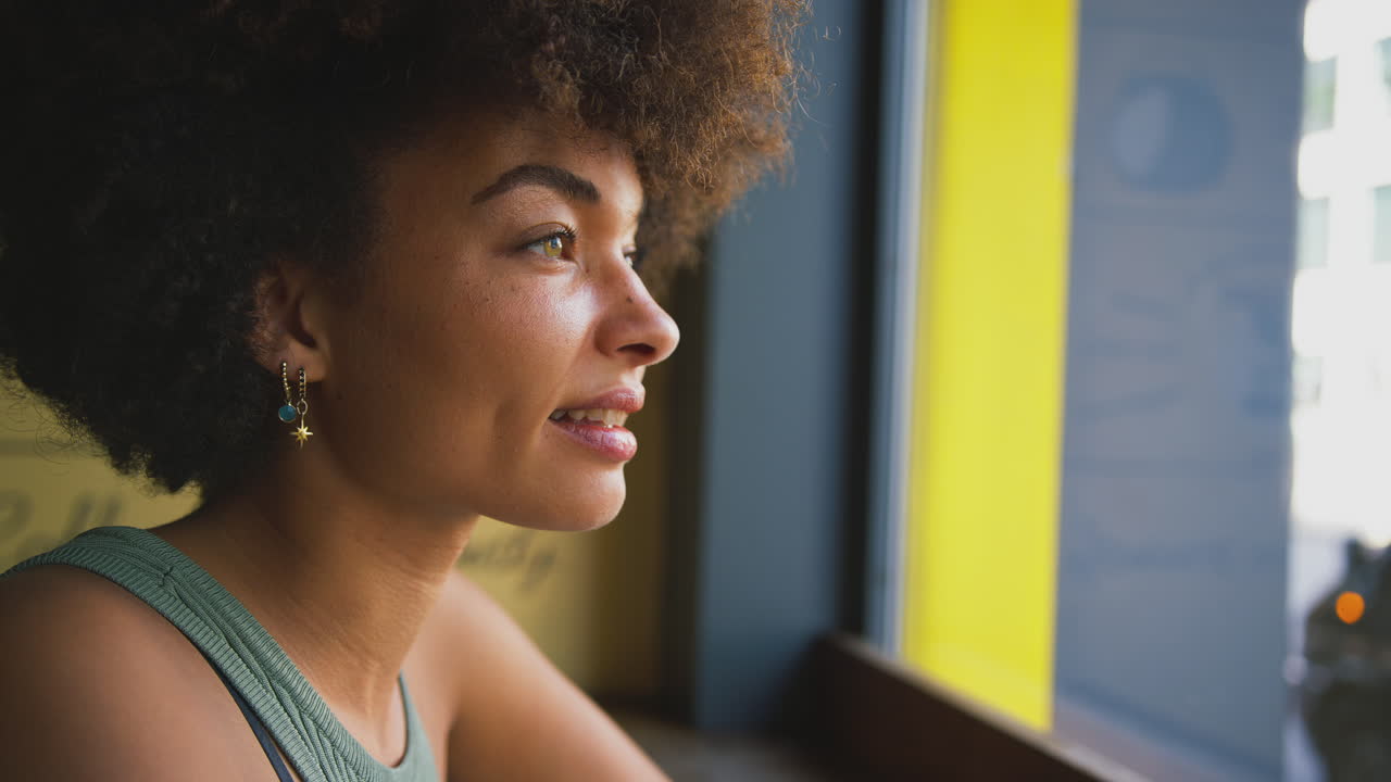 Head And Shoulders Portrait Of Thoughtful Young Woman In Coffee Shop Window