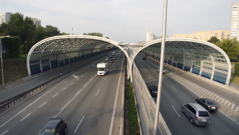 cars drive through a noise barrier in the middle of a residential area