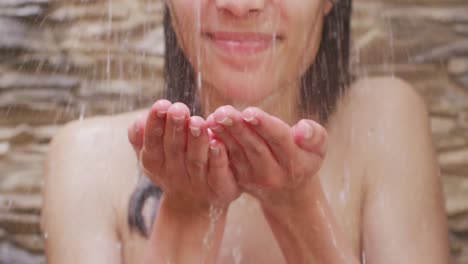 mujer biracial relajándose y duchándose en el baño