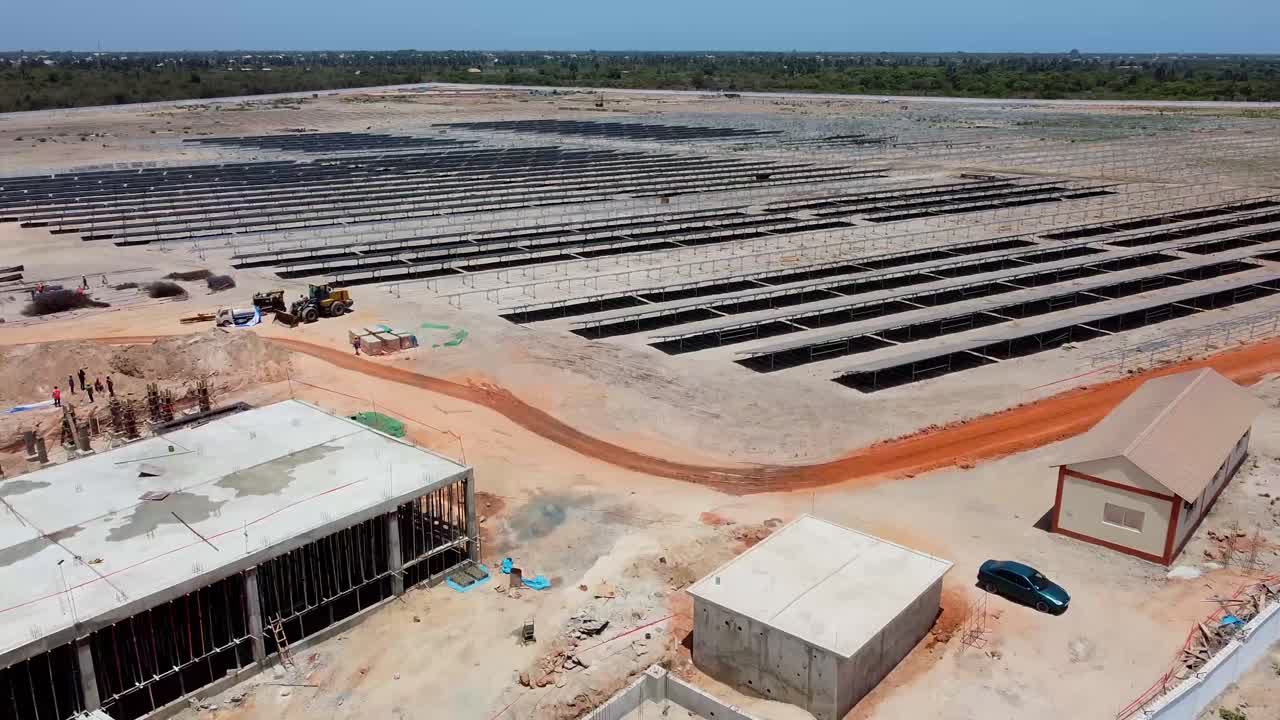 Aerial view of photovoltaic power plant with buildings and solar panels under construction in Jambur, Gambia