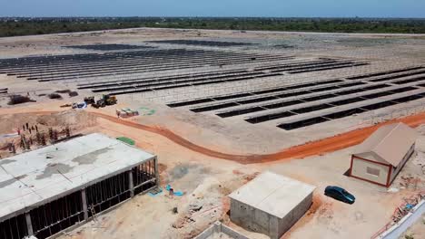 Aerial-view-of-photovoltaic-power-plant-with-buildings-and-solar-panels-under-construction-in-Jambur,-Gambia