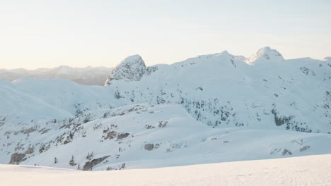 Slow-pan-left-of-a-snowy-mountain-range-during-winter-in-Canada,-BC