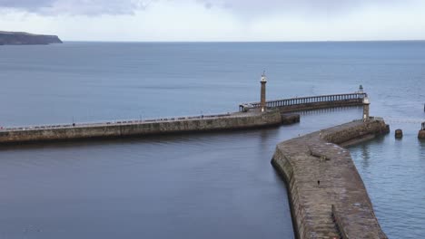 panning shot of whitby harbour revealing the large walls and historic city