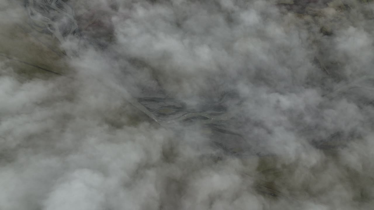 Aerial view of winding rivers partially hidden beneath thick clouds at Hafursey, Iceland, creating a mysterious and serene atmosphere over the volcanic landscape.