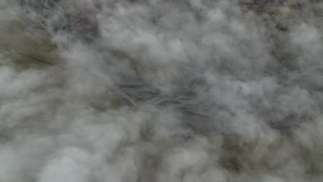 aerial view of winding rivers partially hidden beneath thick clouds at hafursey, iceland, creating a mysterious and serene atmosphere over the volcanic landscape.