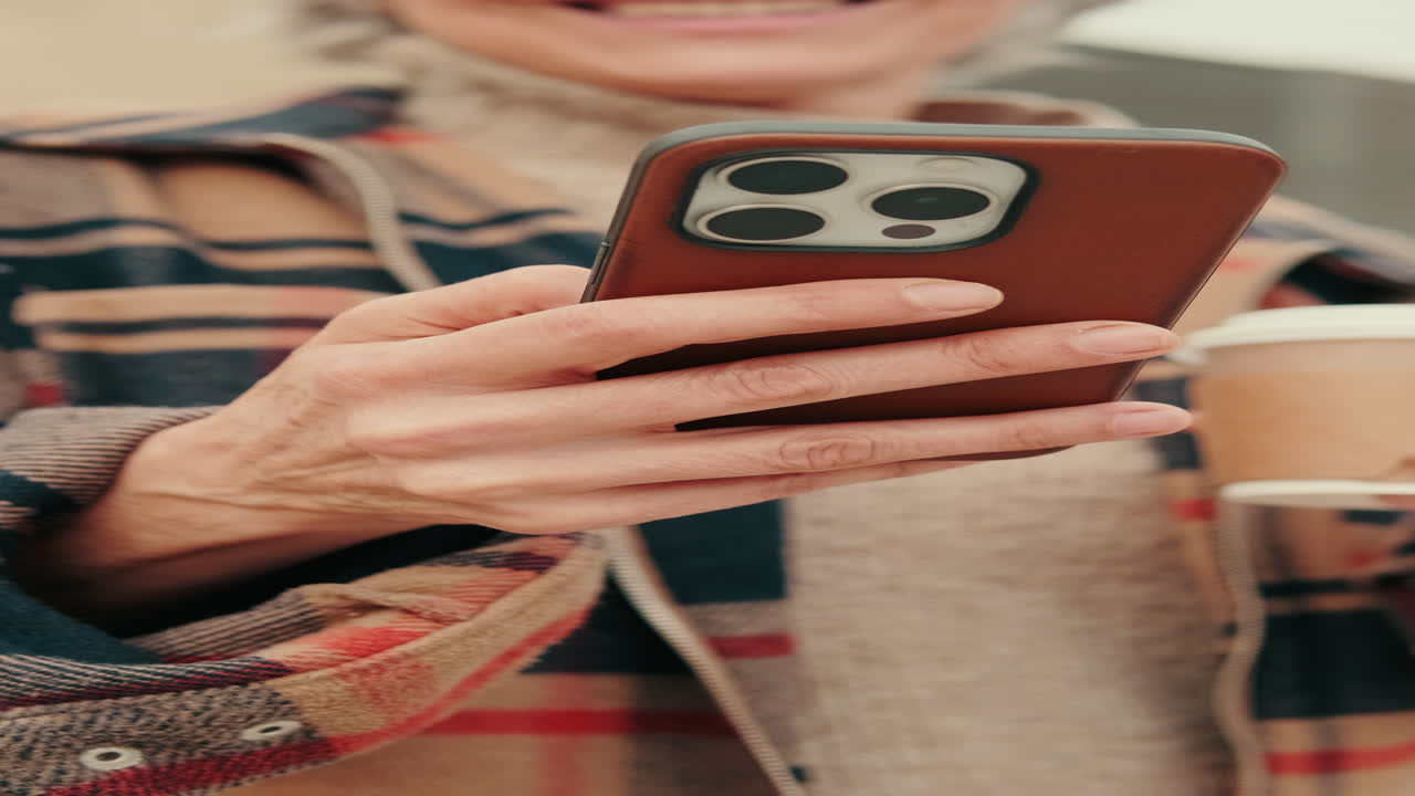 Persona che usa lo smartphone e tiene una tazza di caffè