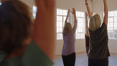 instructor de clase de yoga enseñando a mujeres maduras practicando pose de montaña disfrutando de un estilo de vida saludable en el gimnasio al amanecer.