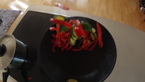 slow-motion video of a chef stirring vegetables in a frying pan in a non-commercial kitchen.