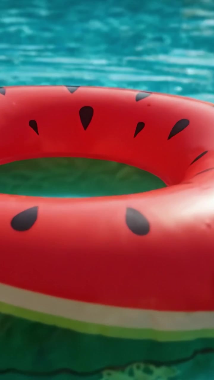 Floating Watermelon Inflatable Ring in Sparkling Pool Water: A Bright and Fun Summer Accessory for Relaxation and Enjoyment in the Sun