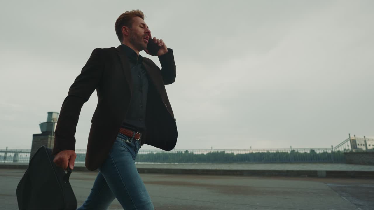 Uomo d'affari che cammina e parla al telefono