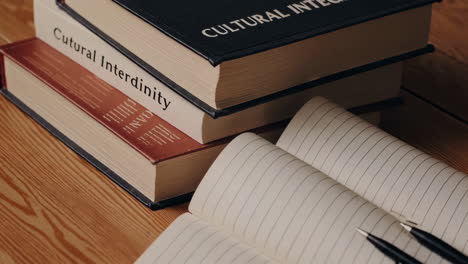 books, notebook, and pens on a wooden table
