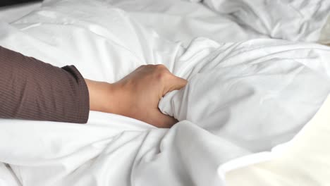 young woman hand squeeze white pillow on bed, closeup