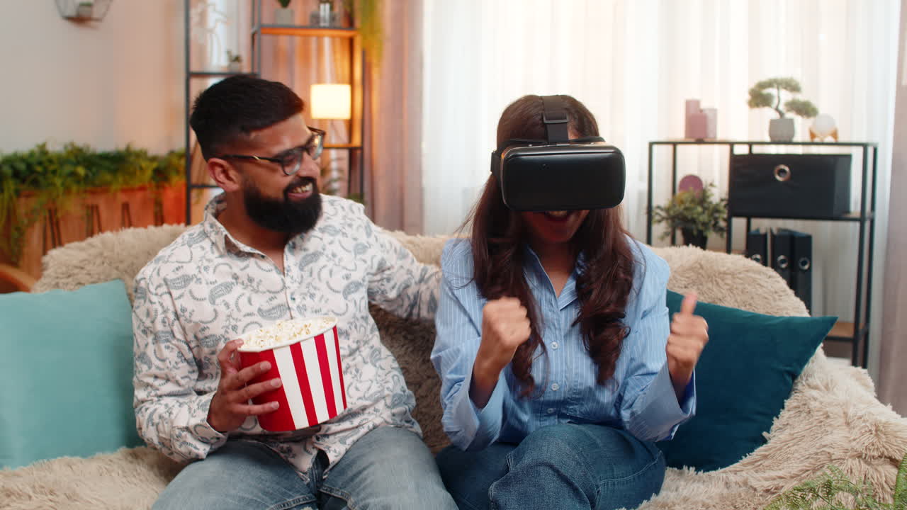 Casal indiano homem mulher usando fone de ouvido VR em casa rindo desfrutando emocionante jogo de realidade virtual