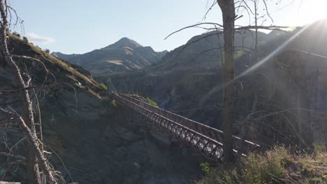 an old bridge above a valley on a sunny summer day at skippers canyon, queenstown, new zealand.
