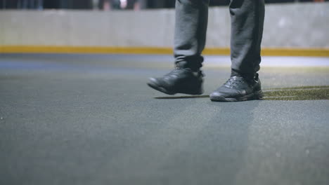 focused view of lady's legs preparing to kick soccer ball against wall during practice, scene captures movement and control on textured playing surface under balanced artificial lighting