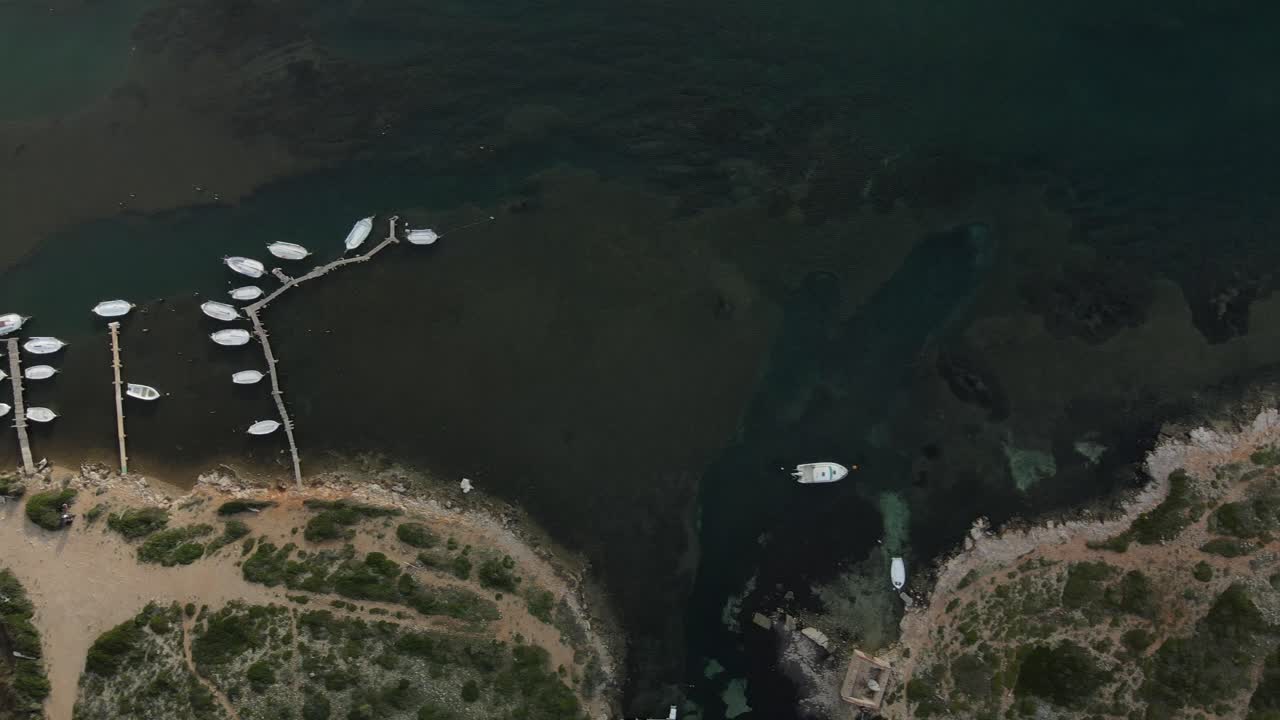 메노르카, 스페인에 있는 sa nitja 자연 항구의 부두를 따라 보트가 정박해 있습니다.
