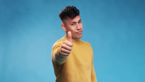 Young man with thumb up to show agreement or approval while standing on an isolated background.