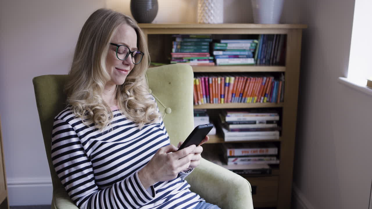 Woman reading a phone while sitting in armchair