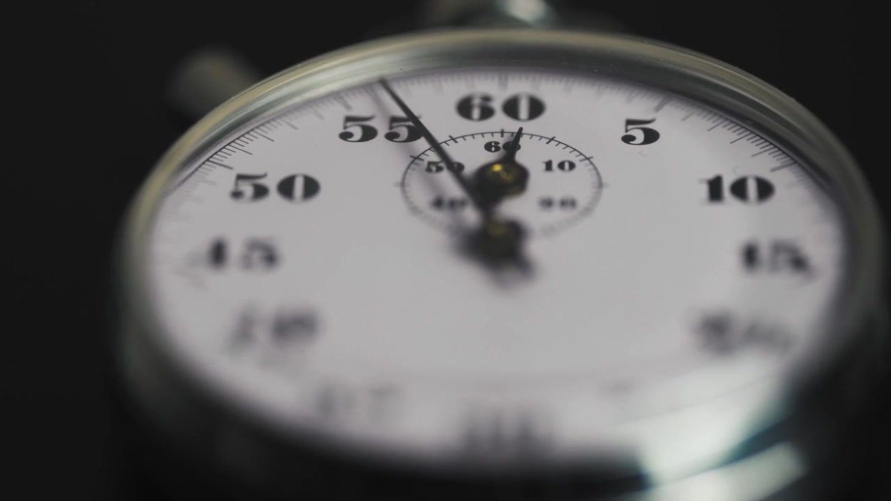Close-up of a Mechanical Stopwatch Ticking on a Dark Background