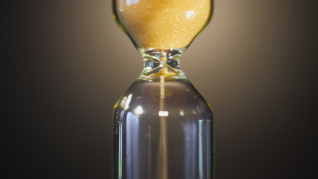 sanduhr. super nahaufnahme von sand, der durch eine sanduhr fließt